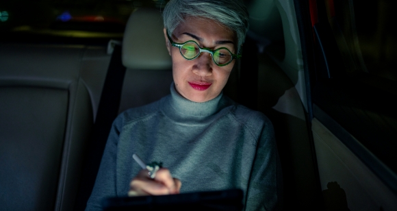 Frau, die im Auto aufs Tablet schaut